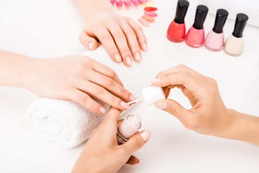 girl holding hands on towel while manicurist applying nail polish.jpg